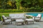 high-end furniture by Seaside Furniture called the DEX collection, with white cushions and teak frame near a swimming pool in the garden