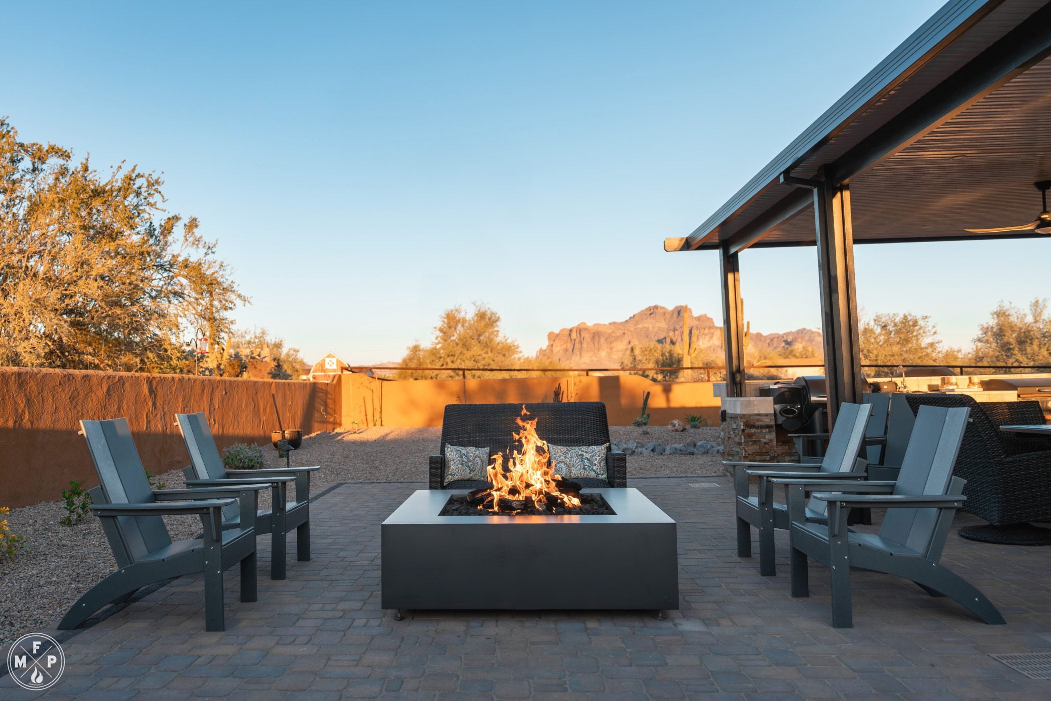 Apache Junction - 56in Glacier Charcoal-43 Close-up of a stainless steel smokeless fire pit with glowing flames in a comforting backyard at dusk.